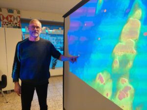 En man står bredvid en stor karta som visar havet och platåbergen som sticker upp.